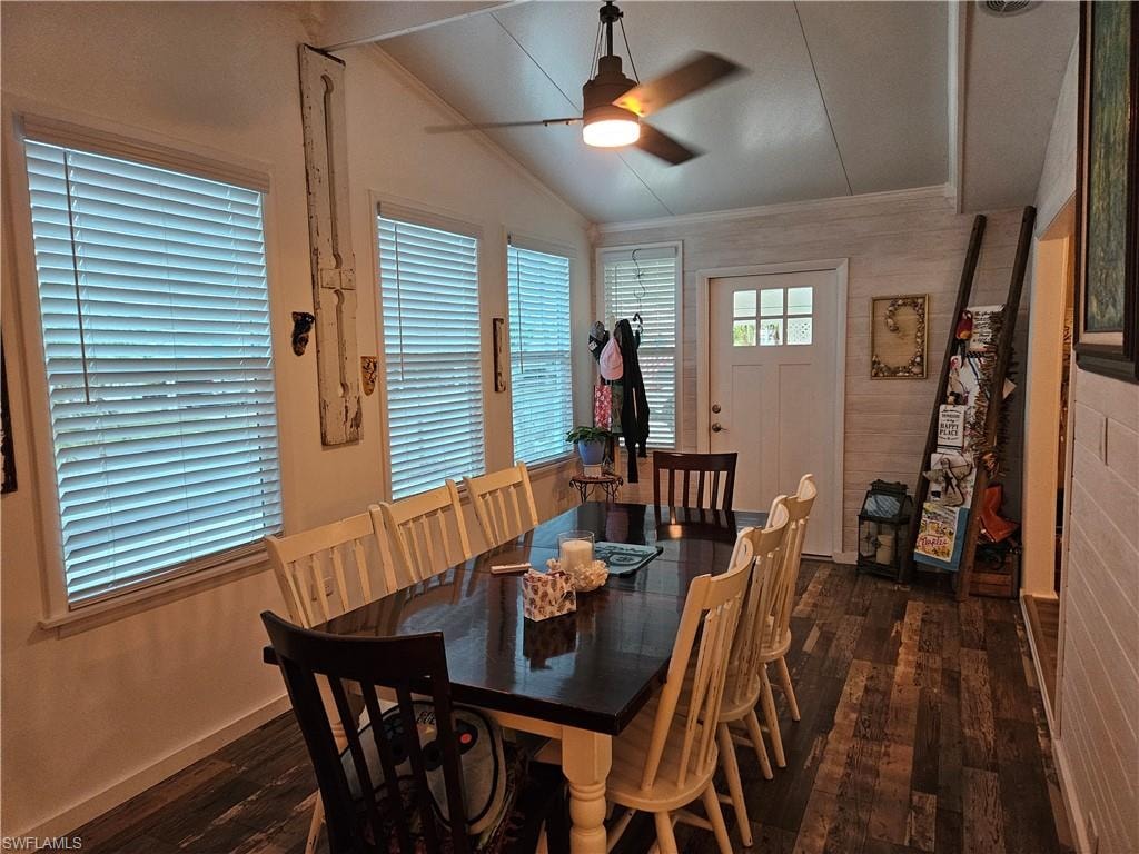 Dining space with dark wood-type flooring, ornamental molding, ceiling fan, and vaulted ceiling