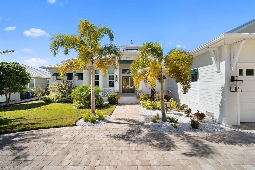 View of front of property with a front lawn, a garage, and french doors