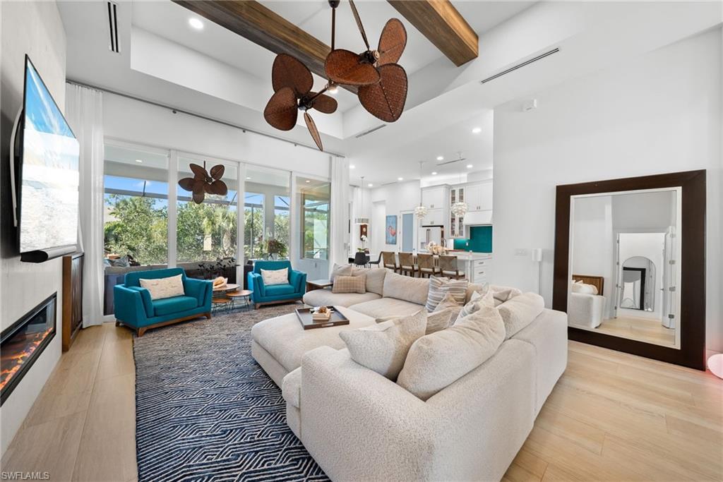 Living area featuring a glass covered fireplace, light wood-type flooring, recessed lighting, and ceiling fan
