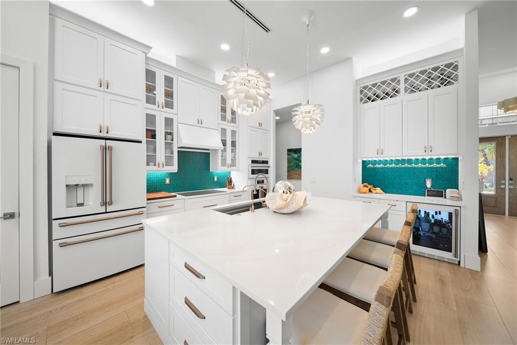 Kitchen featuring high end fridge, glass insert cabinets, and white cabinets