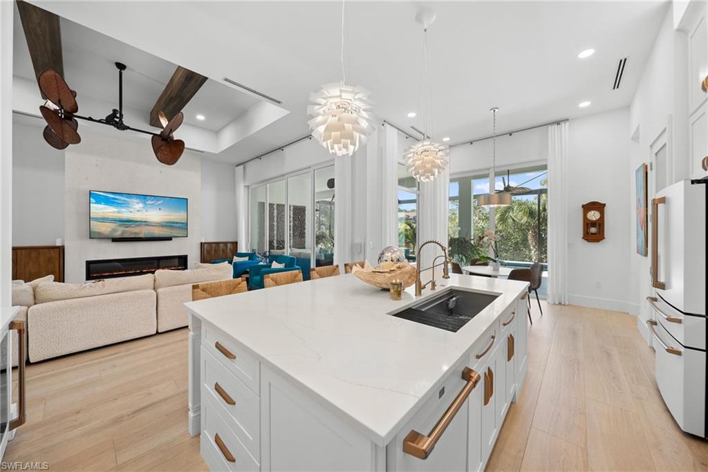 Kitchen featuring white cabinets, pendant lighting, light stone countertops, ceiling fan, and high end fridge