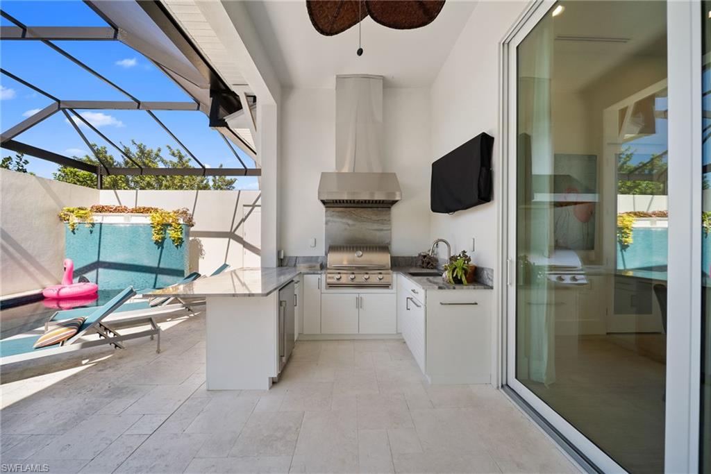 View of patio / terrace with a sunroom, glass enclosure, an outdoor kitchen, and ceiling fan