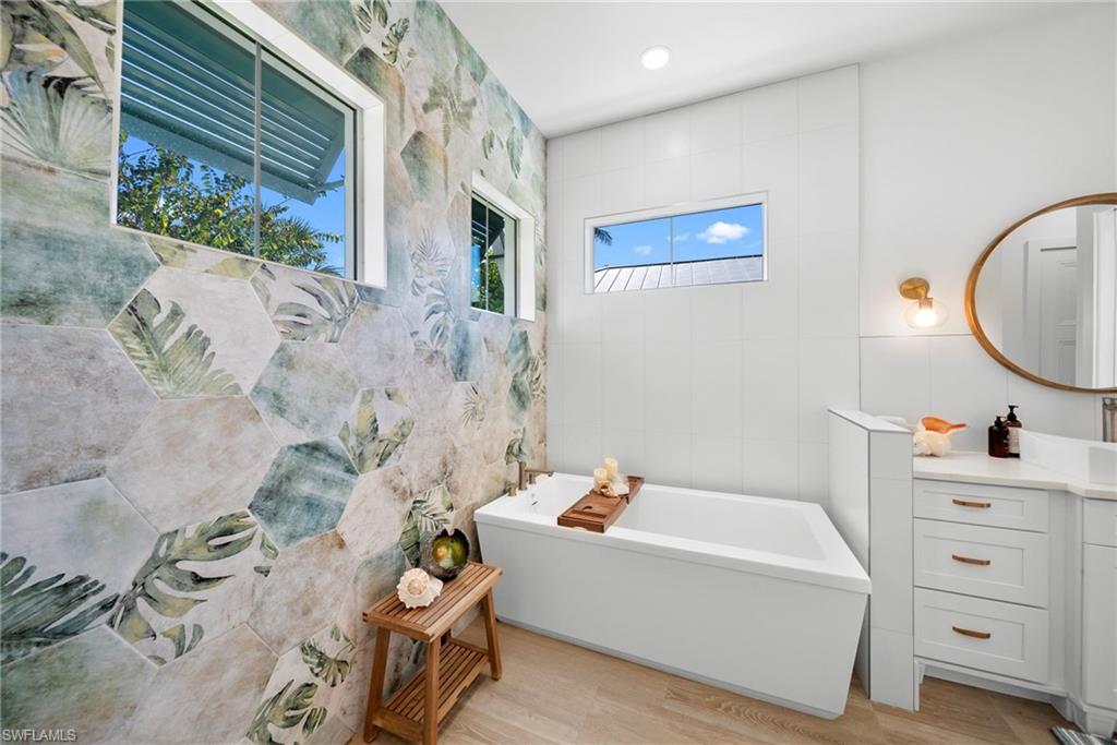 Full bath featuring a freestanding bath, vanity, light wood-style floors, and recessed lighting