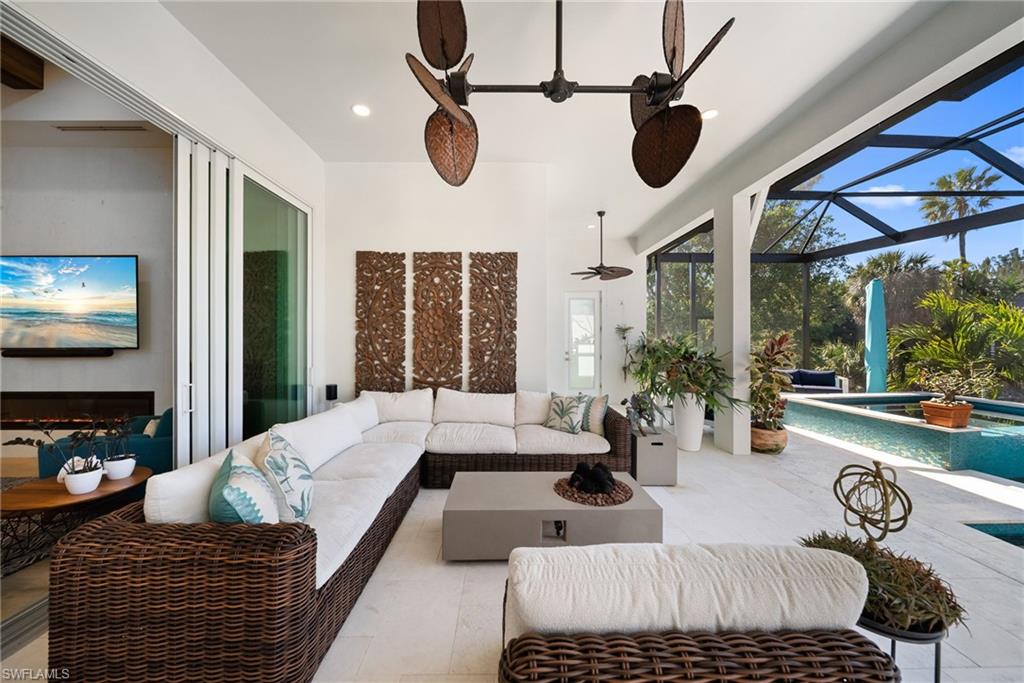 View of patio / terrace with an outdoor living space, a sunroom, a lanai, a ceiling fan, and a pool with connected hot tub