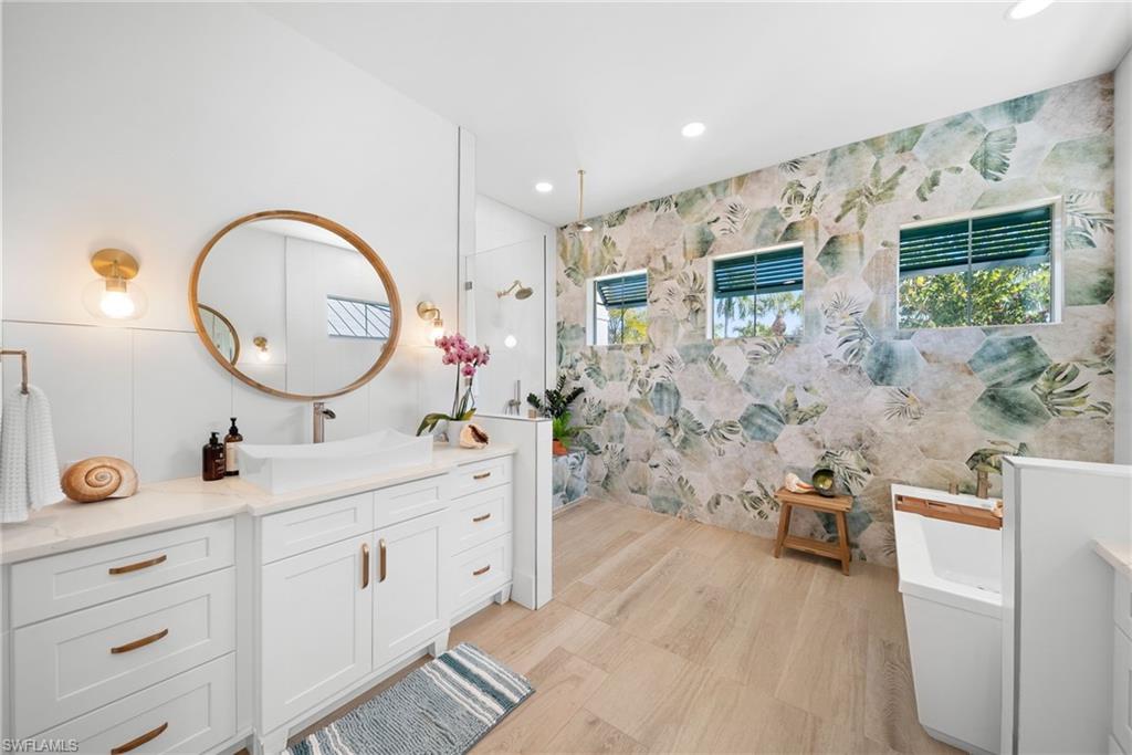 Full bath with walk in shower, a freestanding bath, recessed lighting, vanity, and healthy amount of natural light