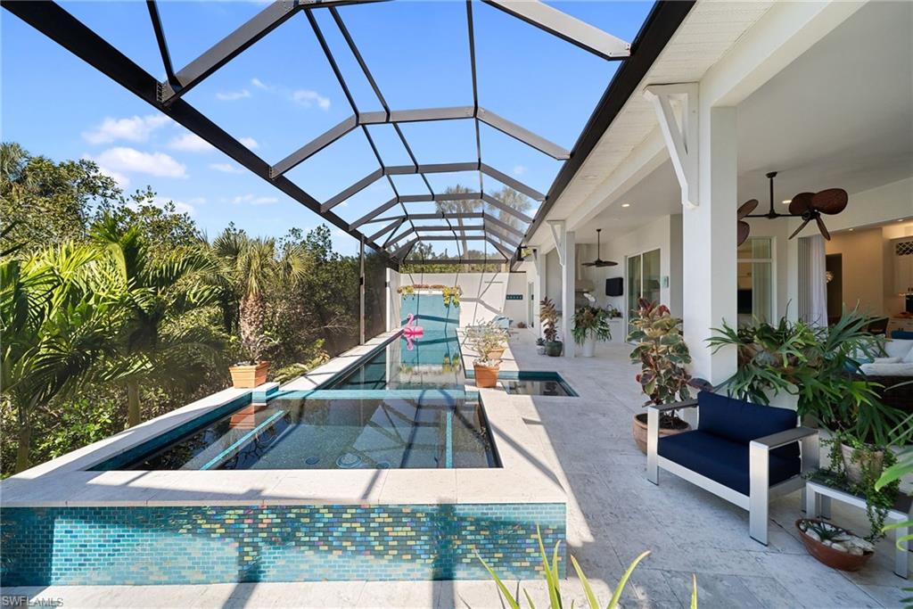 Outdoor pool with a sunroom, a patio, glass enclosure, and a jacuzzi