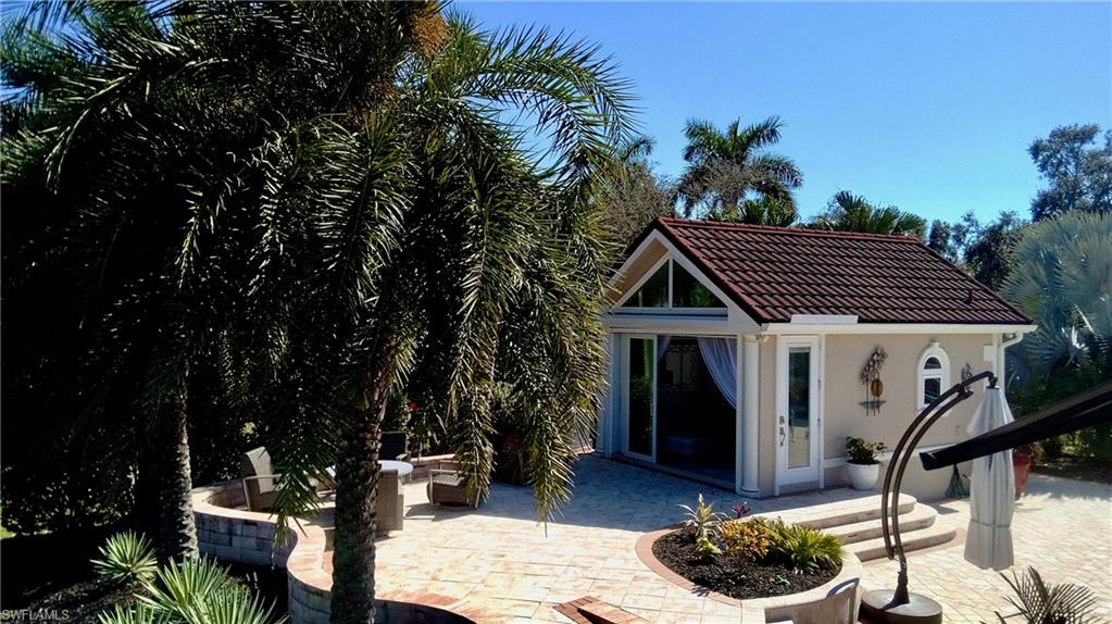 Rear view of property featuring an outdoor structure, a patio area, stucco siding, a tiled roof, and an exterior structure