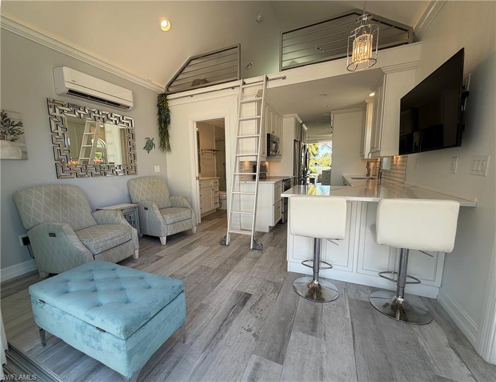 Living room with vaulted ceiling, crown molding, light wood-type flooring, and recessed lighting