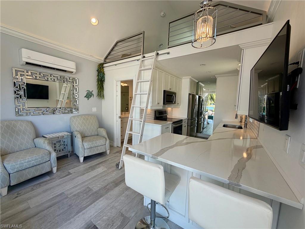 Kitchen featuring a breakfast bar, crown molding, light wood-style floors, stainless steel appliances, and open floor plan