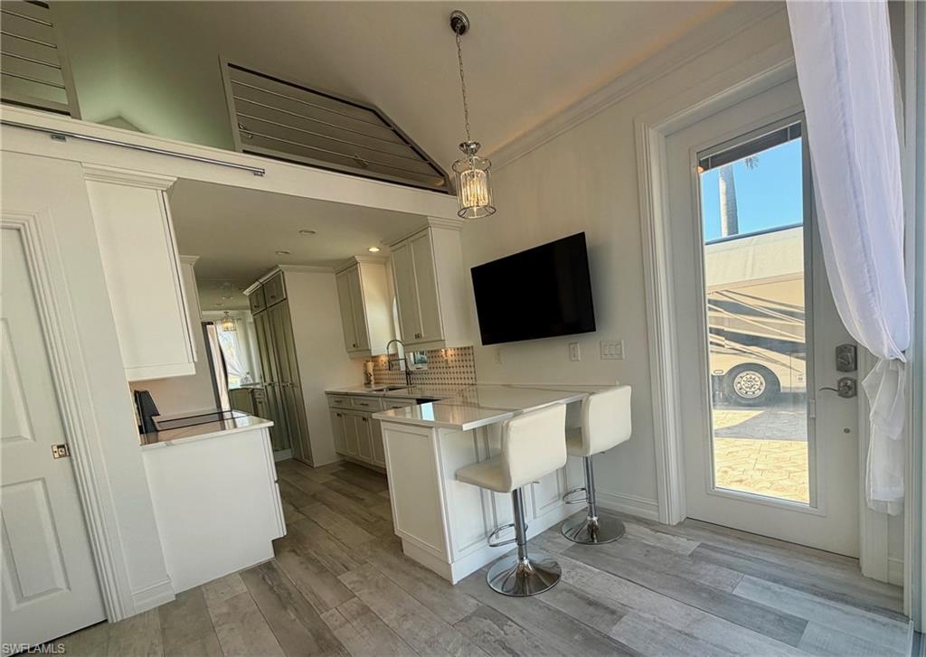 Kitchen with a breakfast bar, a peninsula, healthy amount of natural light, decorative light fixtures, and ornamental molding