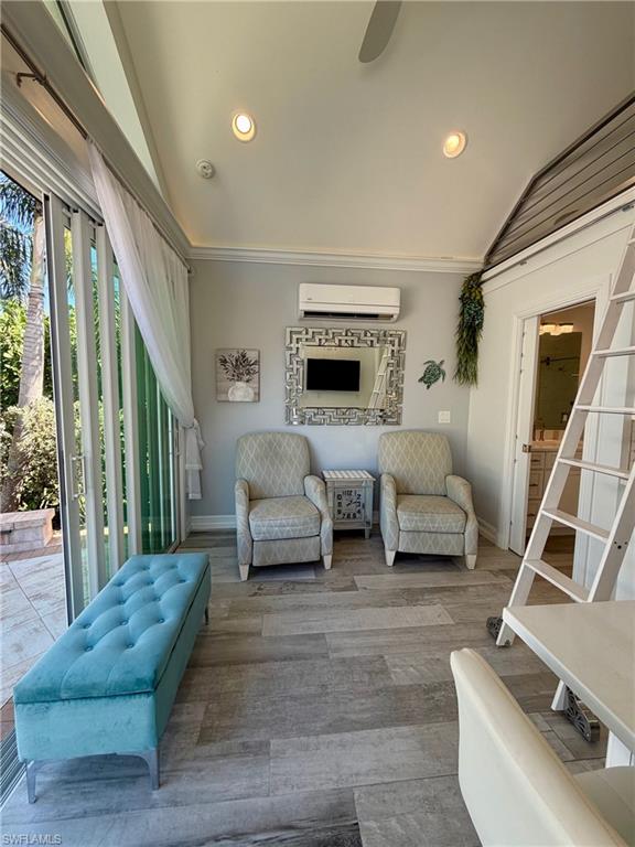 Living area featuring lofted ceiling, a ceiling fan, wood finished floors, recessed lighting, and ornamental molding