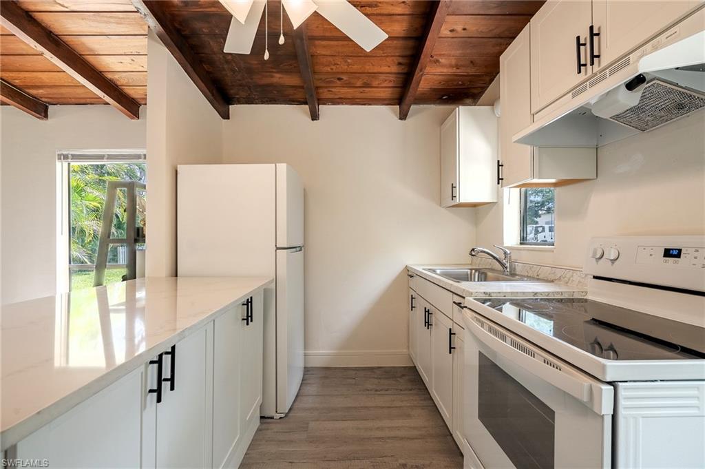 Kitchen with white appliances, white cabinets, a wood ceiling with exposed beams, light wood-style flooring, and ceiling fan