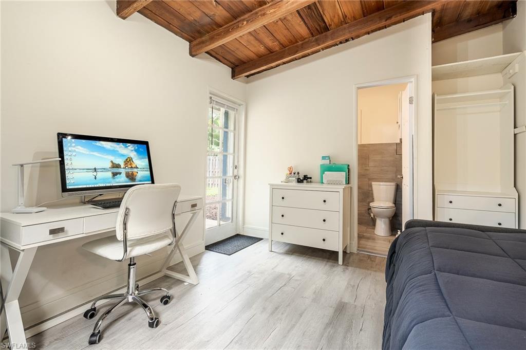 Bedroom featuring wooden ceiling, an office area, light wood-style flooring, access to outside, and lofted ceiling with beams