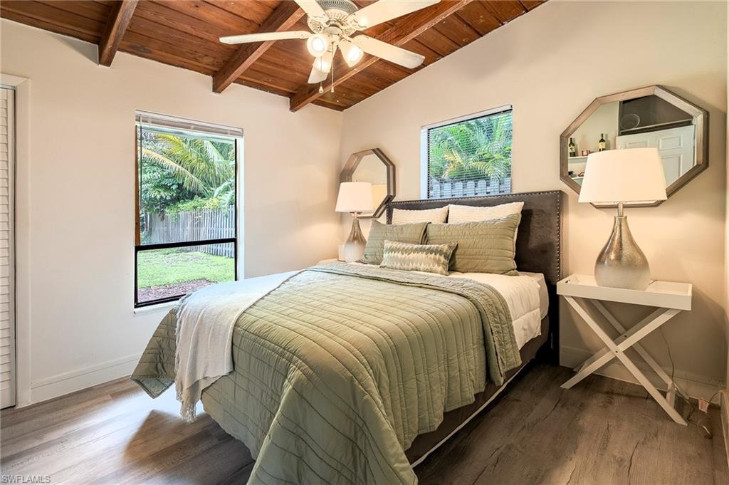 Bedroom with lofted ceiling with beams, wooden ceiling, wood finished floors, and a ceiling fan