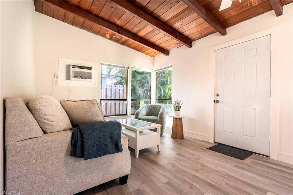Living area featuring lofted ceiling with beams, light wood-style floors, and wood ceiling