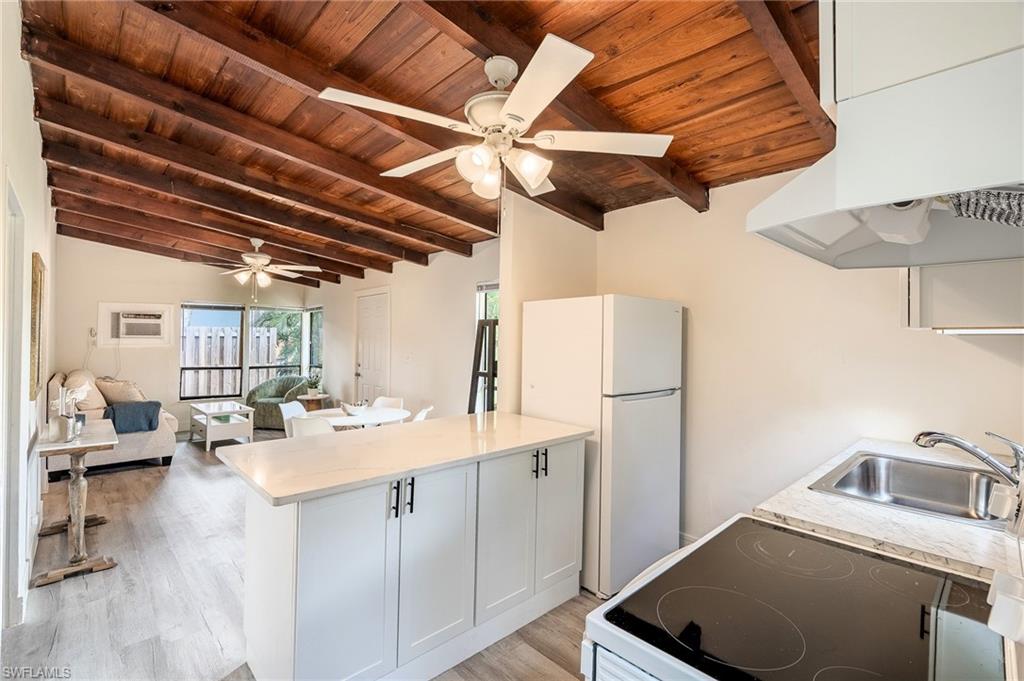 Kitchen with a peninsula, freestanding refrigerator, range with electric cooktop, white cabinetry, and wood ceiling