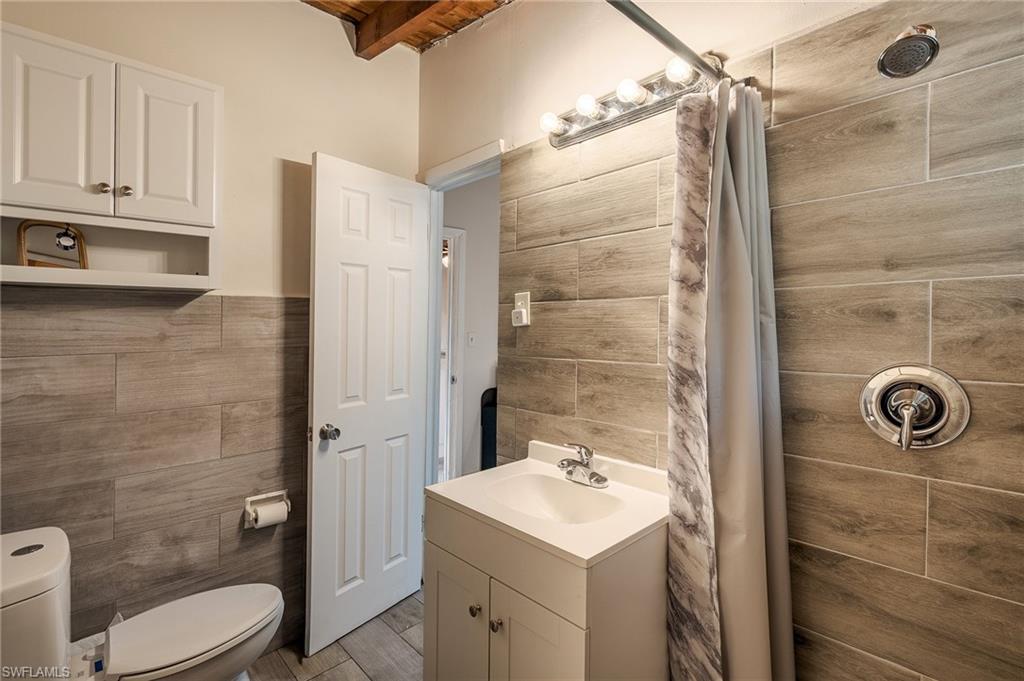 Full bathroom featuring tile walls, a shower stall, vanity, and a wood ceiling with exposed beams