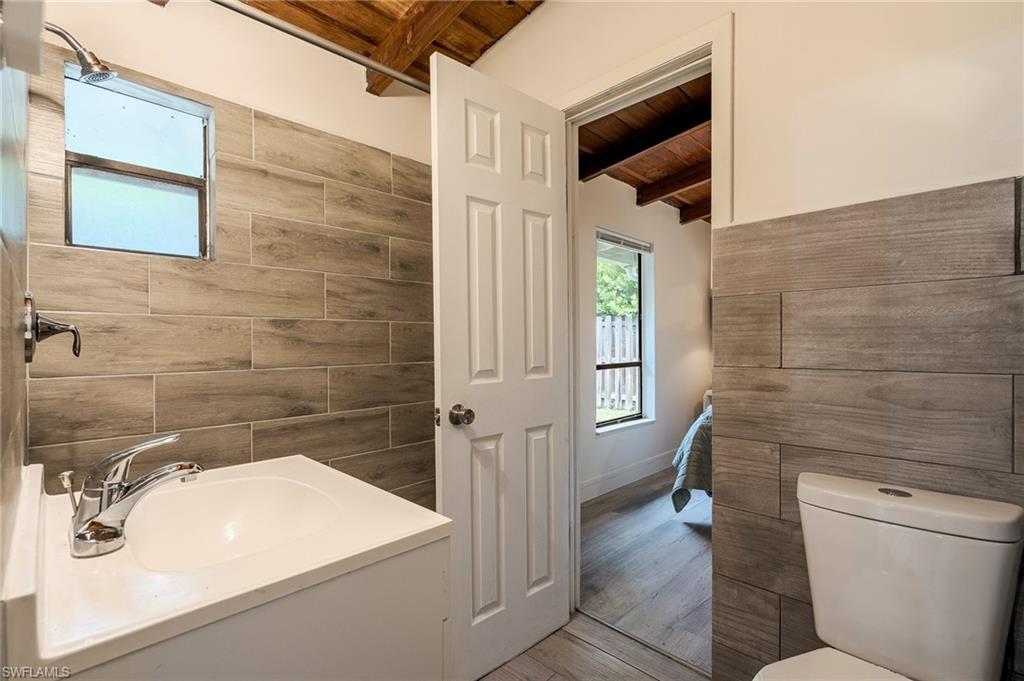 Bathroom with tile walls, a wood ceiling with exposed beams, vanity, and wood finished floors