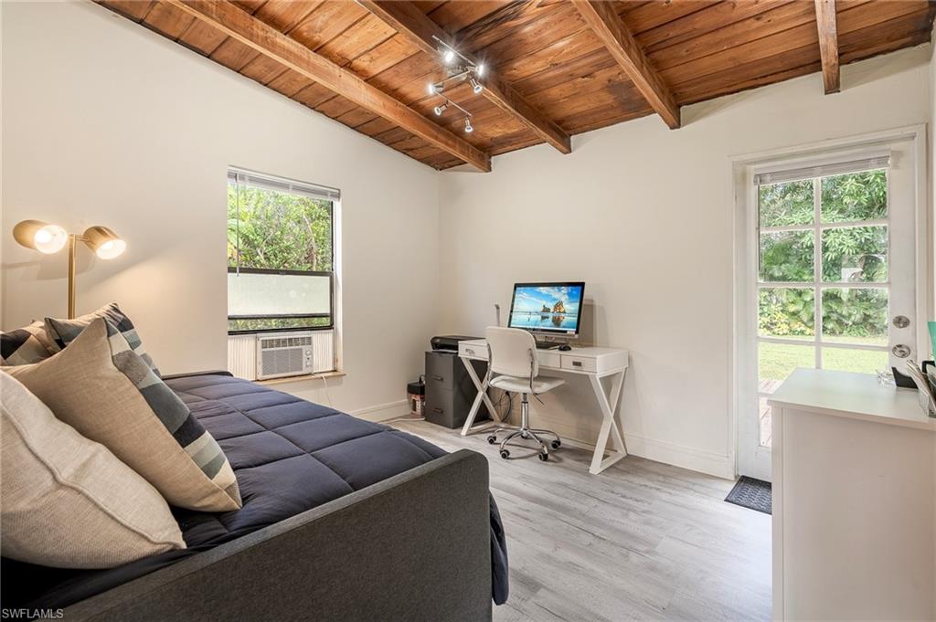 Bedroom with wooden ceiling, an office area, light wood-type flooring, and lofted ceiling with beams