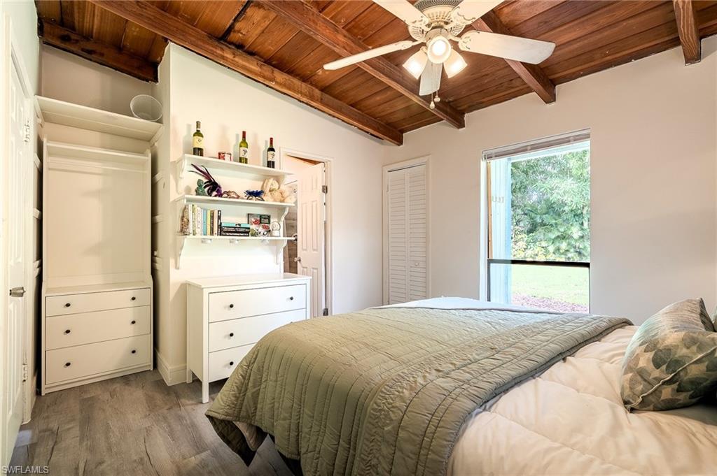 Bedroom with wood finished floors, wooden ceiling, ceiling fan, and vaulted ceiling with beams