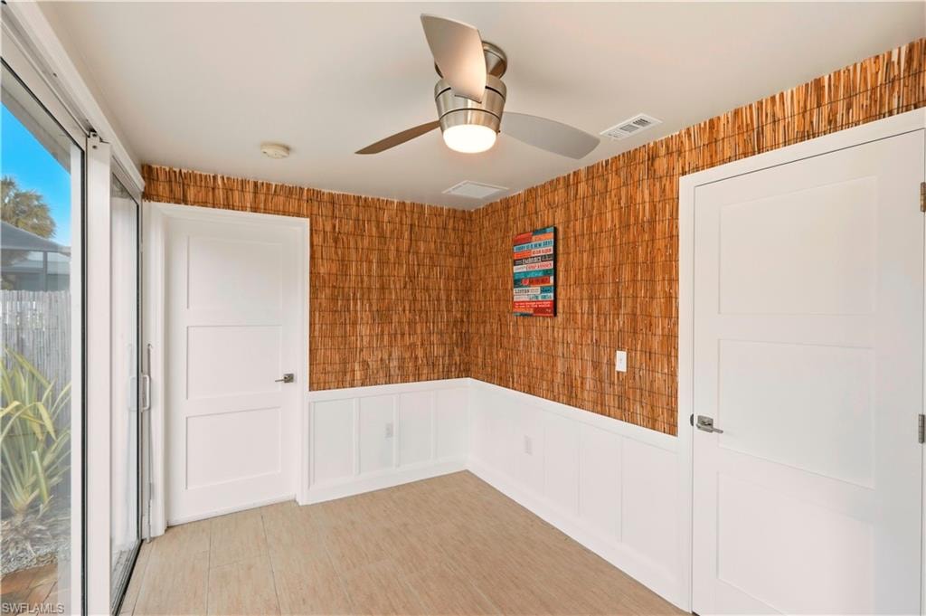 Kitchen featuring white cabinets, stainless steel microwave, backsplash, and light stone countertops