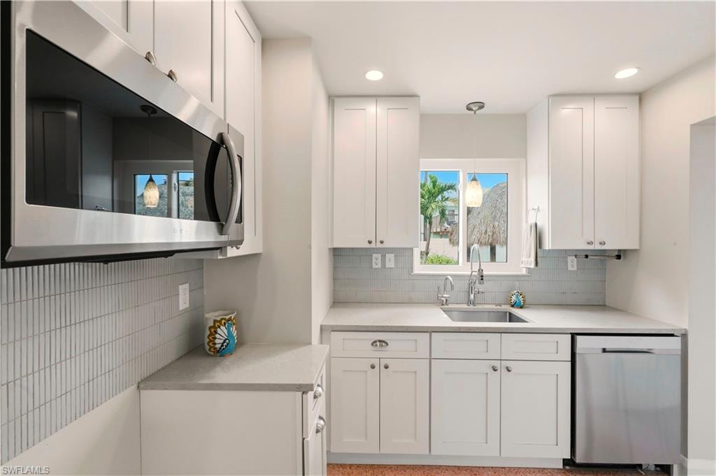 Kitchen featuring white cabinets, stainless steel appliances, and light stone counters