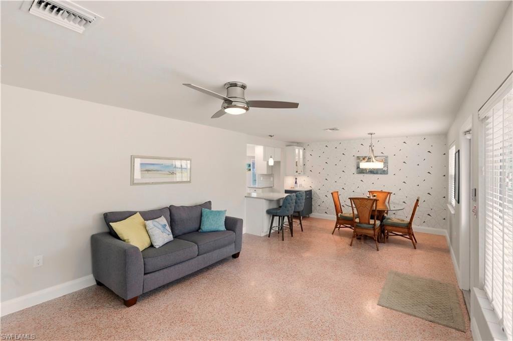 Living area with ceiling fan and dark aggregate flooring