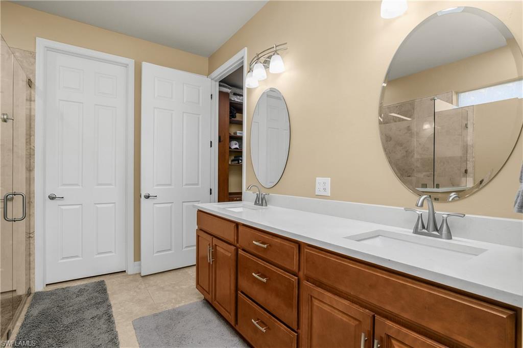Full bath with a stall shower, double vanity, and light tile patterned floors
