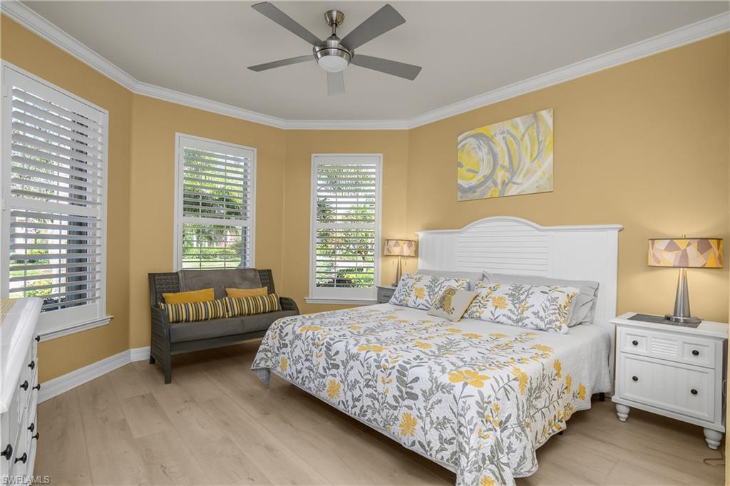 Bedroom with light wood-style floors, a ceiling fan, and crown molding