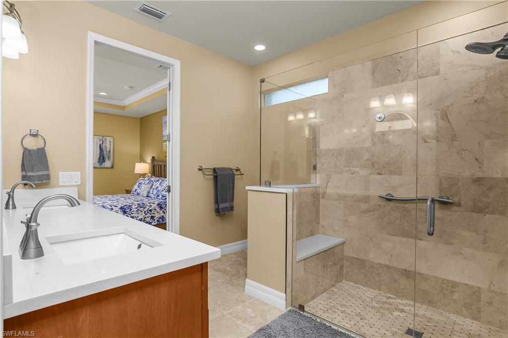Ensuite bathroom featuring double vanity, a stall shower, recessed lighting, light tile patterned flooring, and crown molding