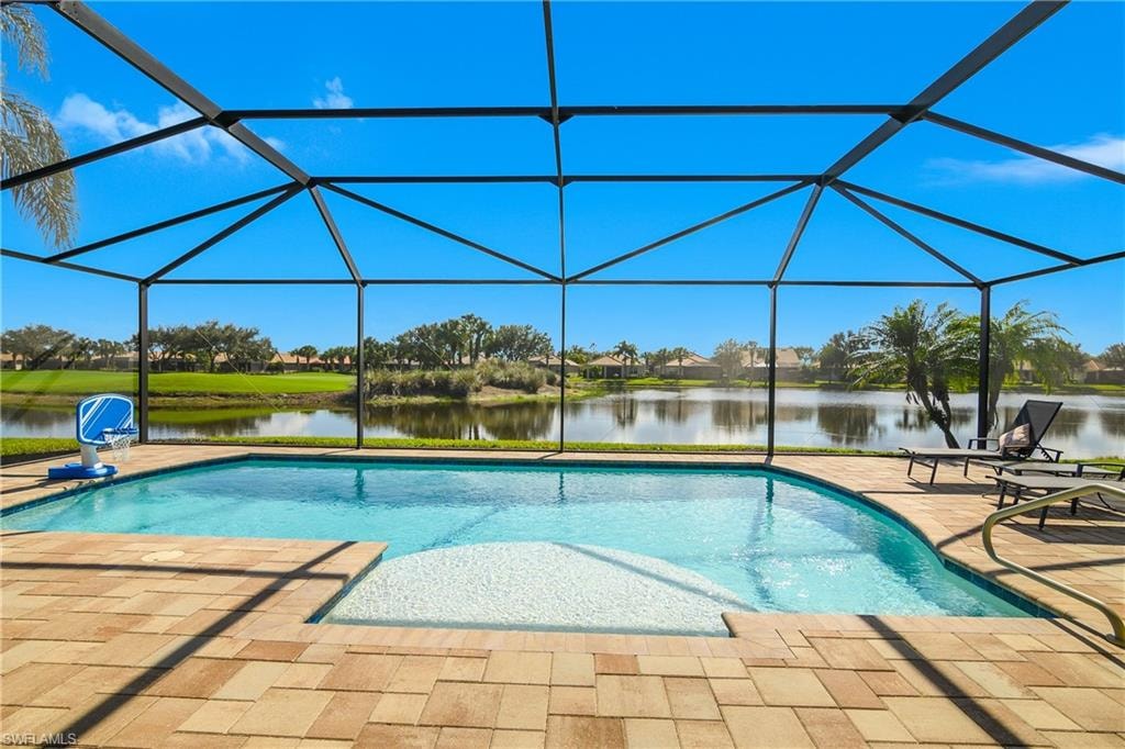 Swimming pool featuring a sunroom, a water view, glass enclosure, and a patio