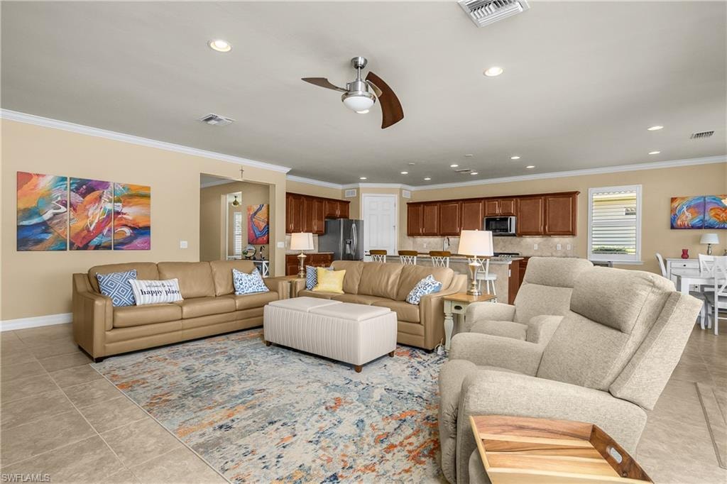 Living room featuring ceiling fan, ornamental molding, recessed lighting, and light tile patterned flooring