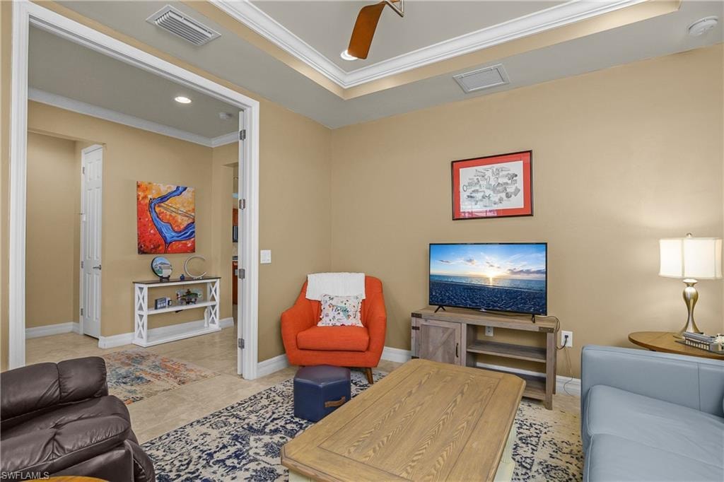 Tiled living area featuring ornamental molding, ceiling fan, recessed lighting, and a tray ceiling