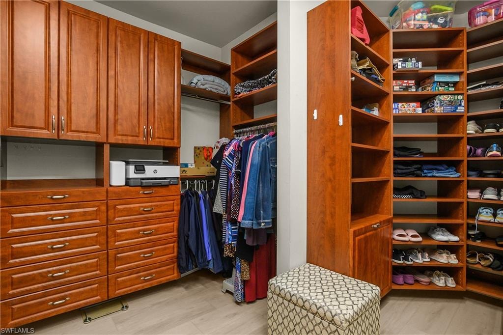 Walk in closet with light wood-style floors