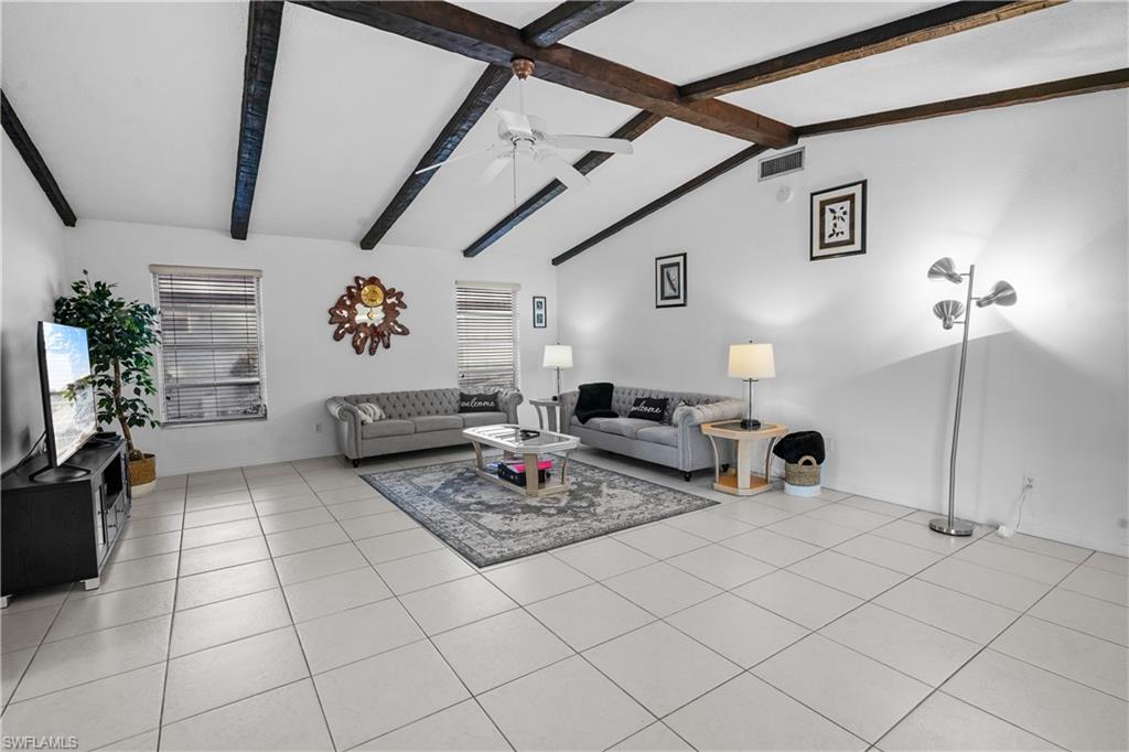 Kitchen featuring a kitchen bar, stainless steel appliances, white cabinetry, light countertops, and lofted ceiling with beams