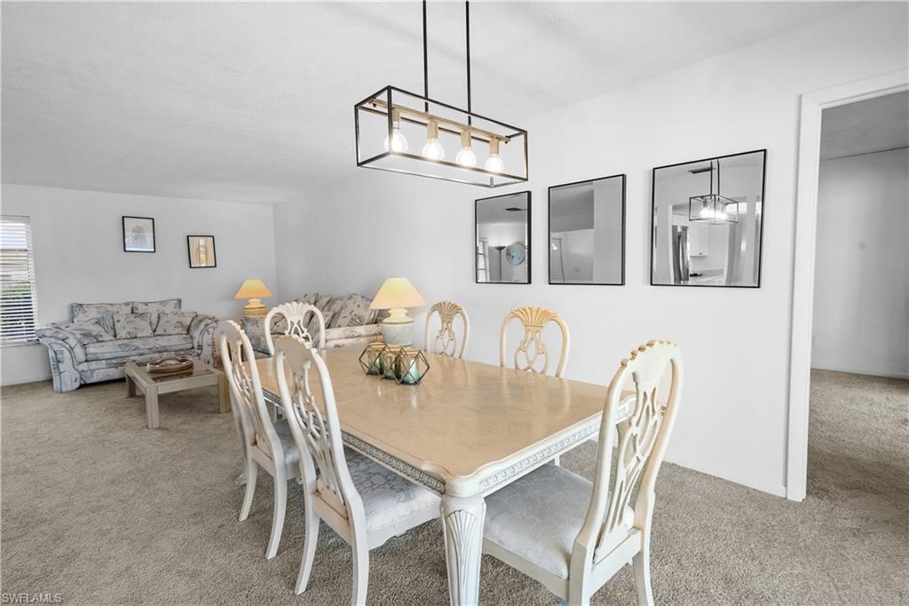 Dining area featuring light colored carpet opens to the pool.