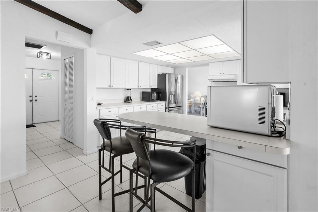 Kitchen with stainless steel appliances, light countertops, white cabinets, a breakfast bar / peninsula. Great acces to the pool and covered lania!