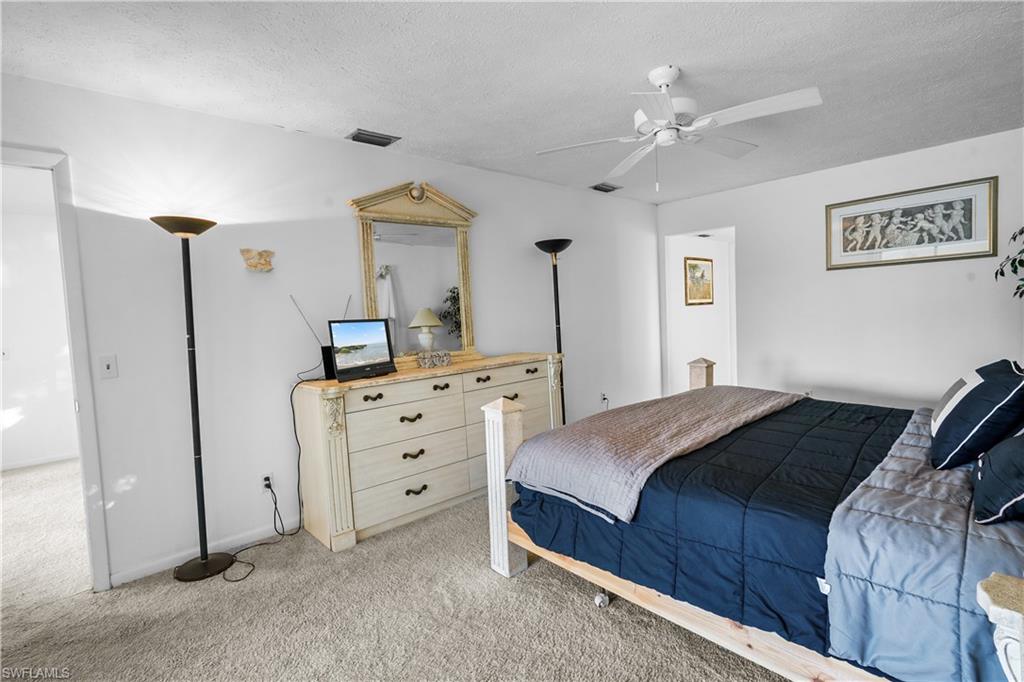 Bedroom with light colored carpet, ceiling fan, and a spacious closet