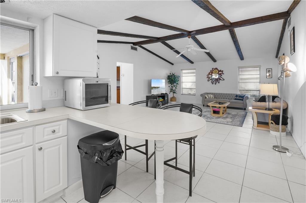Kitchen with white cabinets, light countertops, stainless steel french door refrigerator with ice dispenser. Also nicely appointed with small appliances for a turnkey kitchen.