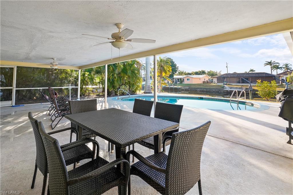 Solar heated swimming pool featuring a large covered patio area, outdoor dining space, and grilling area