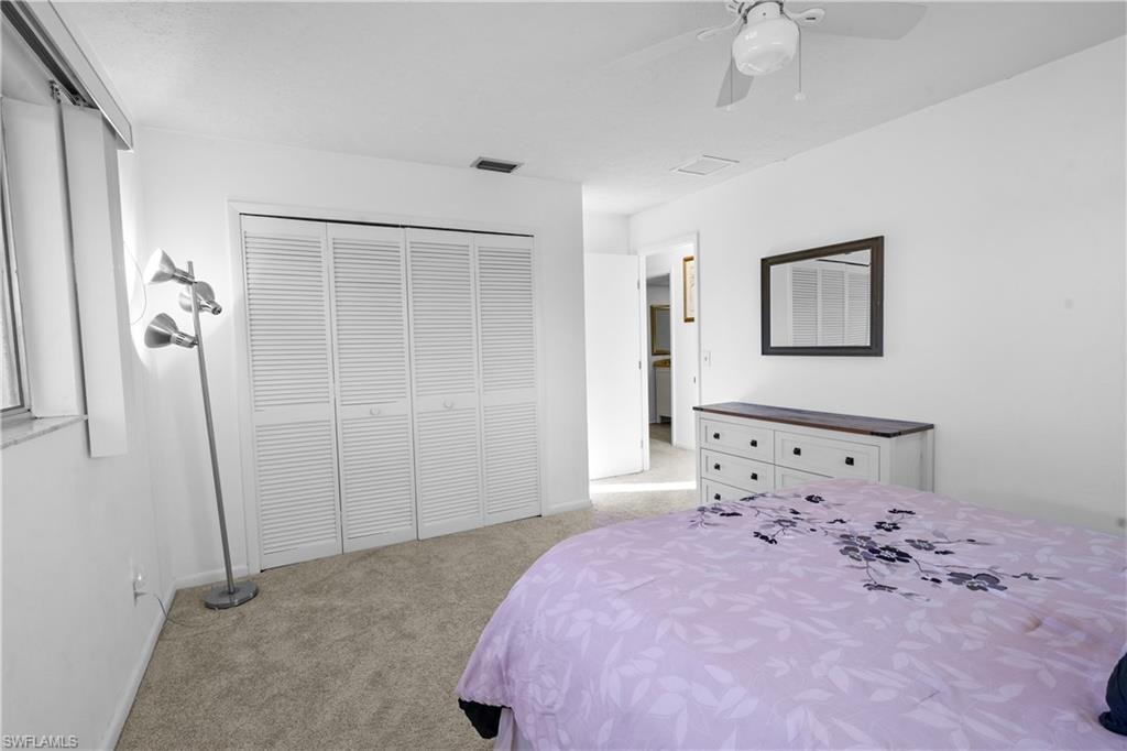 Guest Bedroom #2 featuring carpet floors, multiple windows with window coverings a ceiling fan and large closet.