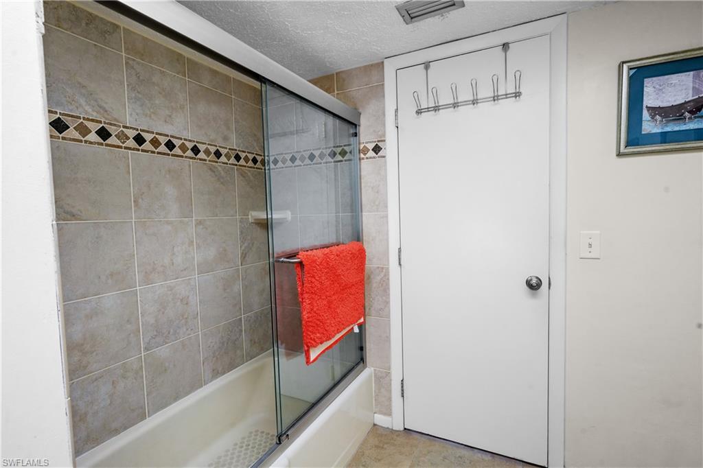 Full bath featuring two vanities, a combo tub bath. The guest bath opens to the pool.