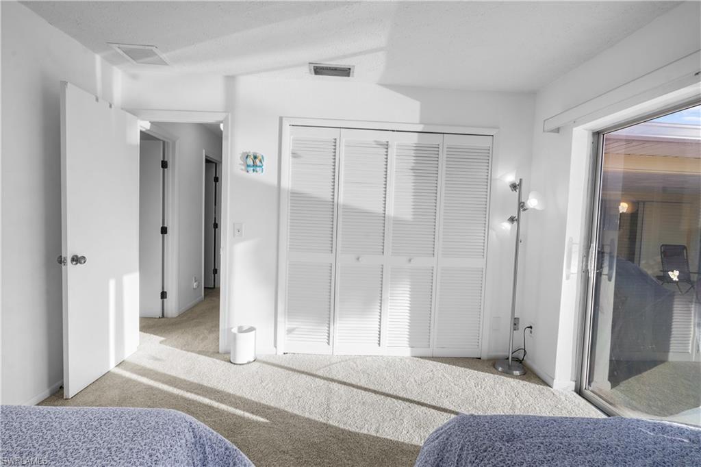 Guest bedroom #1 with patio doors to the pool, carpet, ceiling fan and window coverings.