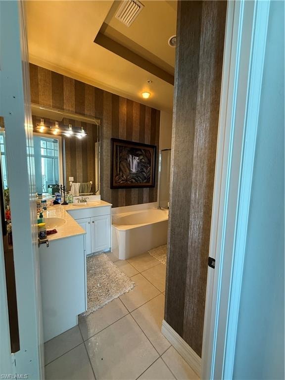 Full bathroom featuring wallpapered walls, a bath, double vanity, and light tile patterned floors