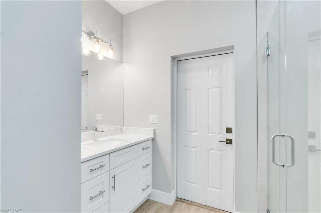 Full bath with a shower stall, vanity, and light wood-style flooring