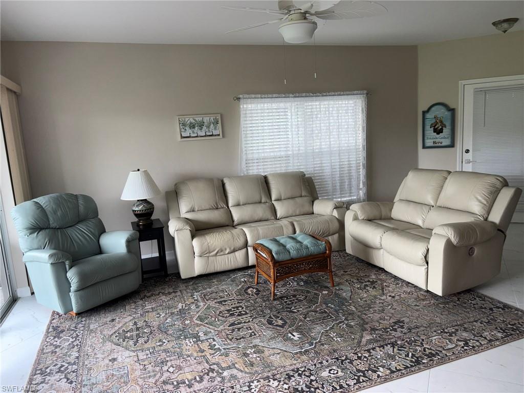 Spacious room featuring light-colored walls, tile flooring, and a ceiling fan