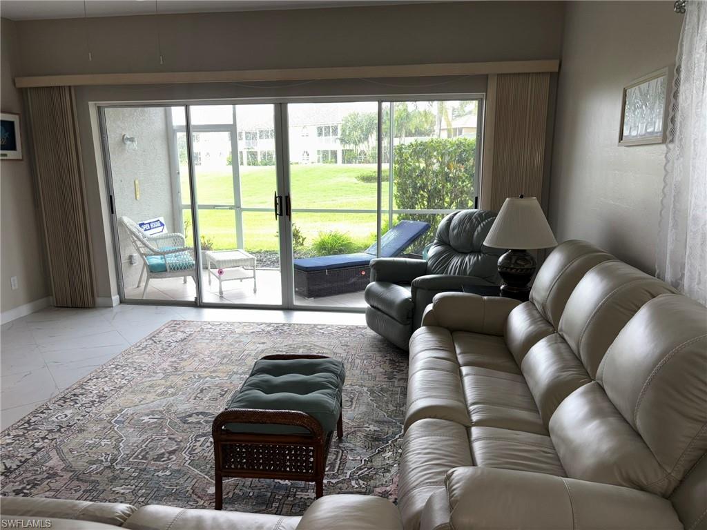 Spacious living area featuring large sliding glass doors opening to a screened lanai and green space beyond