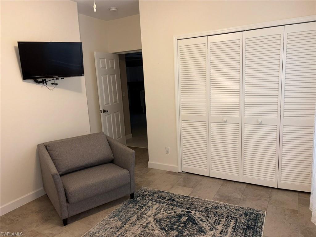 White louvered closet doors with round knobs, light-toned wall paint, and neutral floor tiling