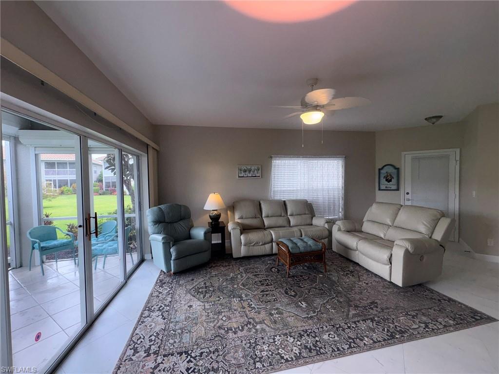 Living area featuring large format tile flooring, a ceiling fan with integrated lighting, and direct access to a screened lanai through sliding glass doors