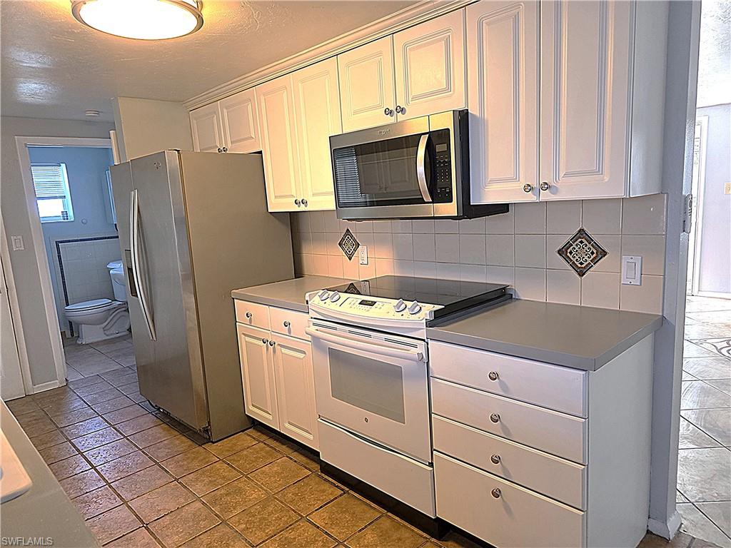 Kitchen featuring stainless steel appliances, white cabinets, backsplash, and a textured ceiling